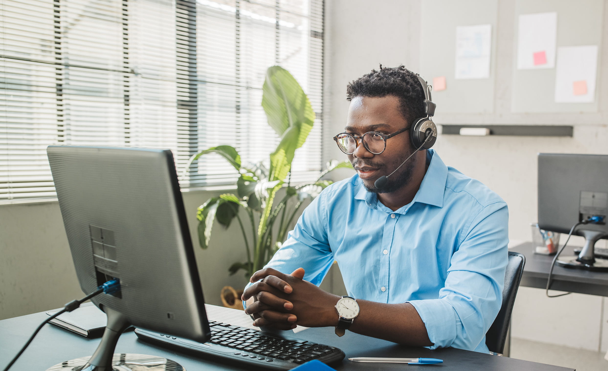 Man in blue shirt at computer with headset