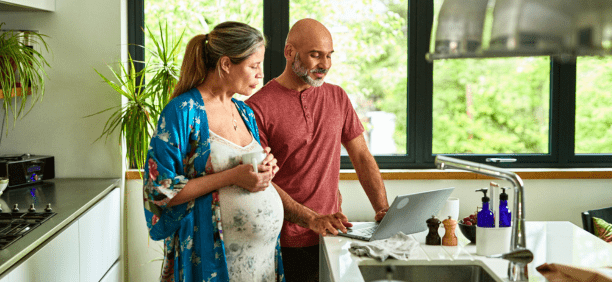 Couple expecting child review information on a computer