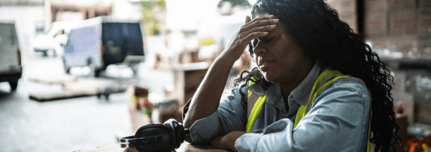 Stressed warehouse worker with her hands to her forehead.
