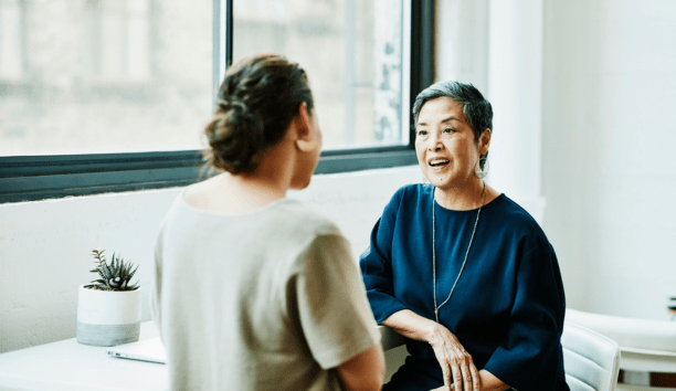 Benefits administrator meeting with an employee as they face each other.