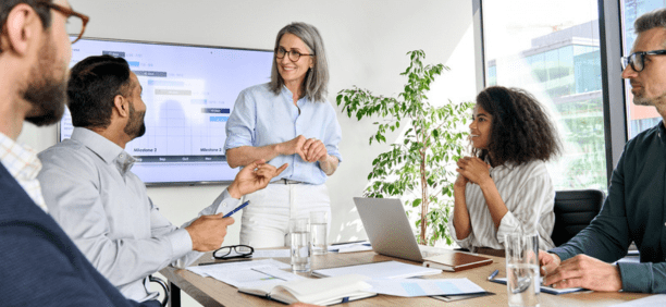 Female leader talking to employees in a conference room. 
