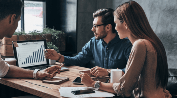 Three coworkers working together while looking at a laptop. 