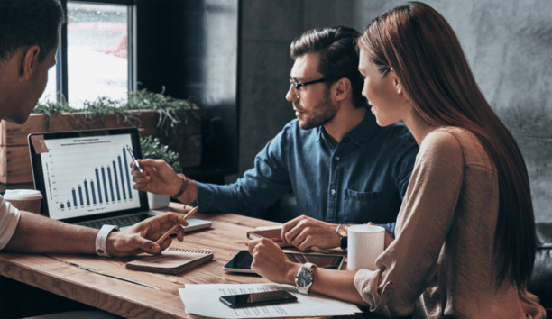 Three coworkers working together while looking at a laptop. 