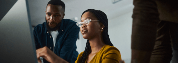 Three employees looking at a laptop.