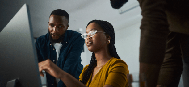 Three employees looking at a laptop.