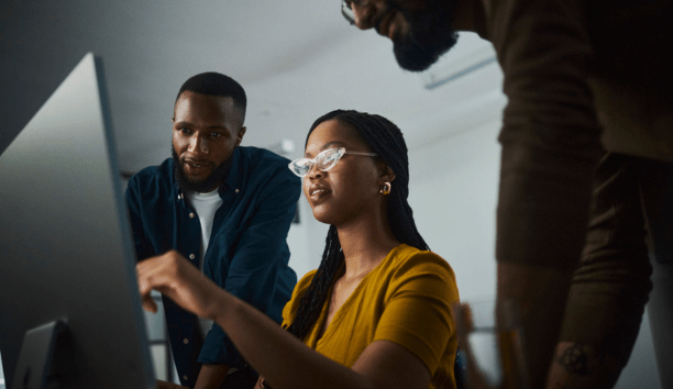 Three employees looking at a laptop.