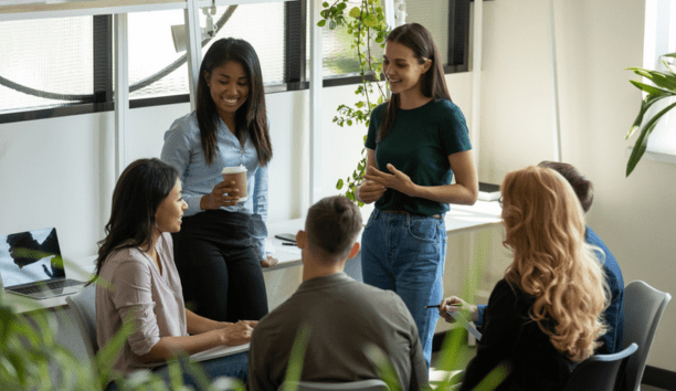 Young adult employees talking and laughing in a conference room.